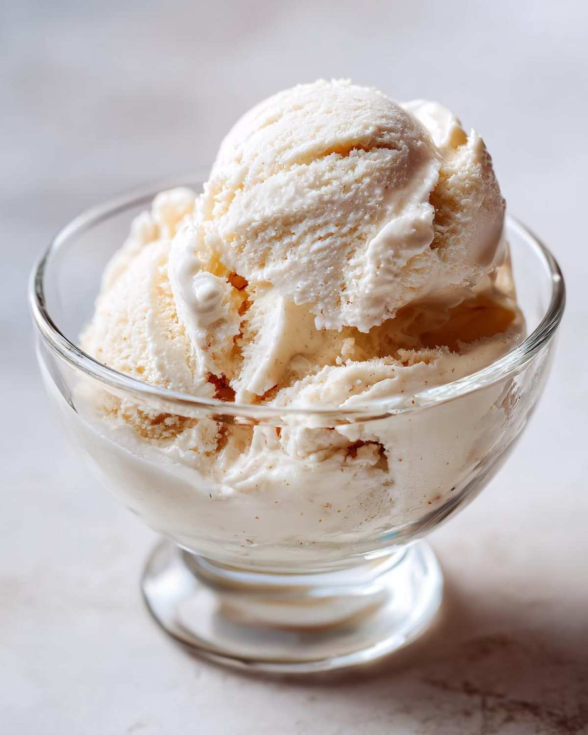 Zbliżenie na lody waniliowe w szklanej miseczce, idealne do przepisu na lody z maszynki.