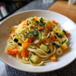 Zbliżenie miski z makaronem spaghetti z kawałkami marchewki i cukinii, posypanym świeżymi ziołami, idealny makaron z warzywami blw.