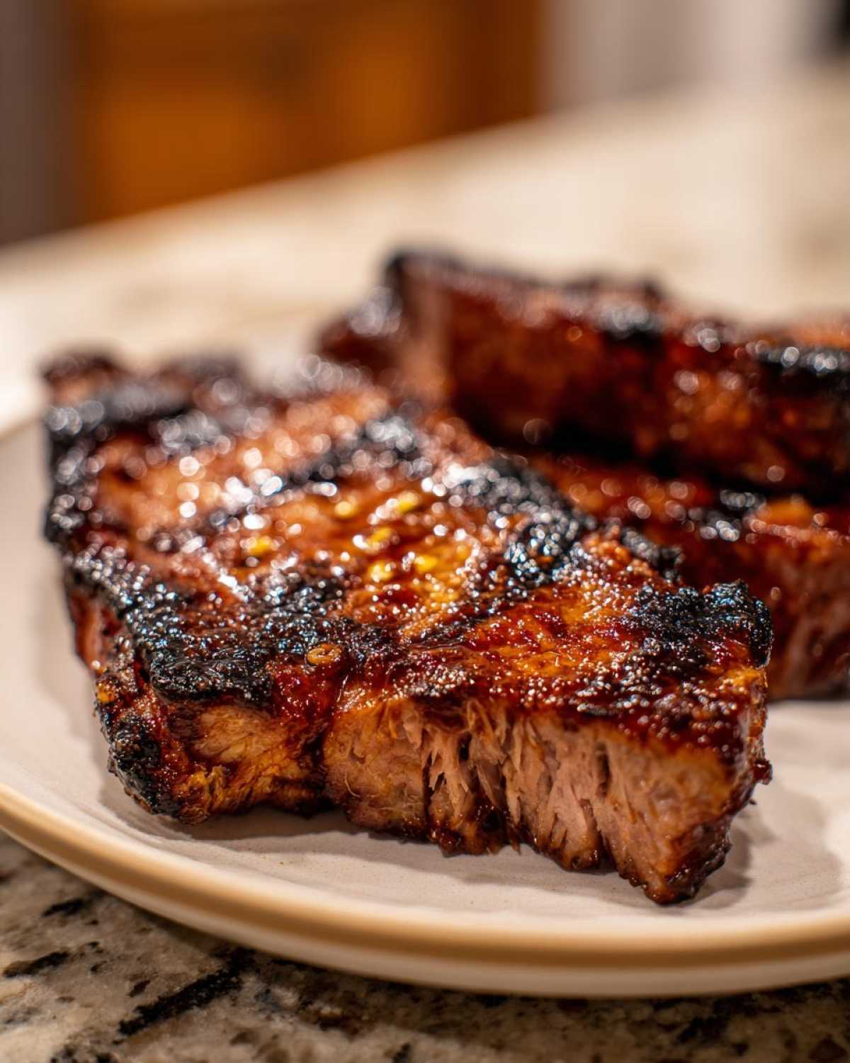 Zbliżenie na kawałek grillowanej karkówki z widocznym przekrojem, pokrytej błyszczącą marynatą. marynata do karkówki na grilla.