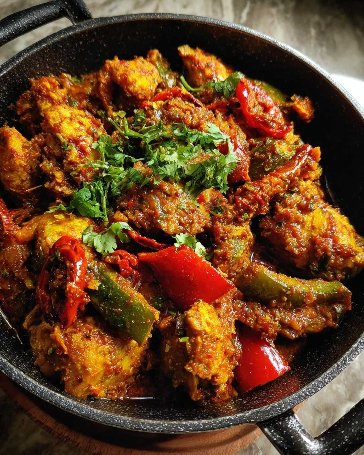 Zdjęcie z bliska kurczaka curry z mlekiem kokosowym w garnku, udekorowanego świeżą kolendrą i papryką.