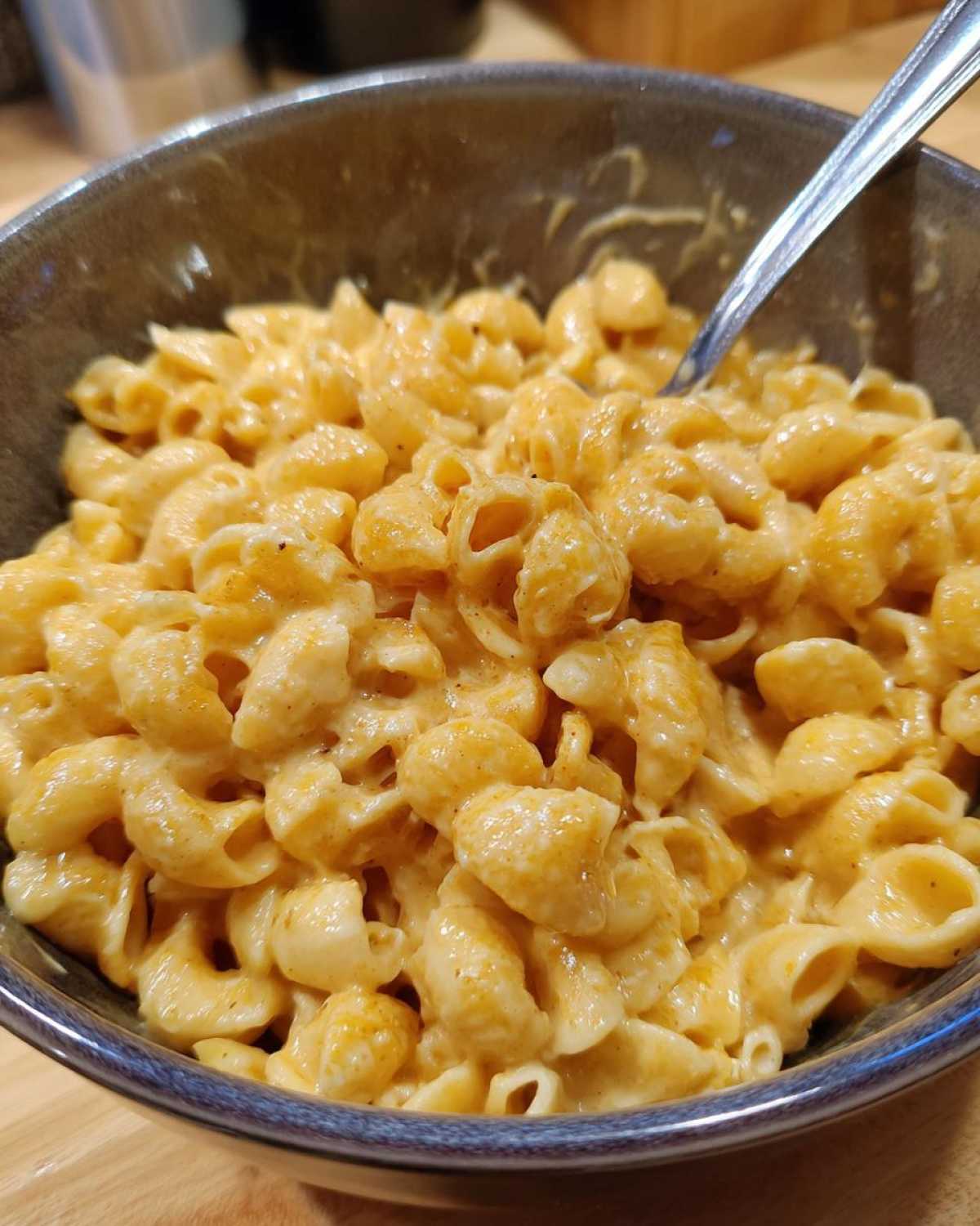 Zdjęcie z bliska makaronu z serem w misce, z łyżką. Idealny makaron z serem.