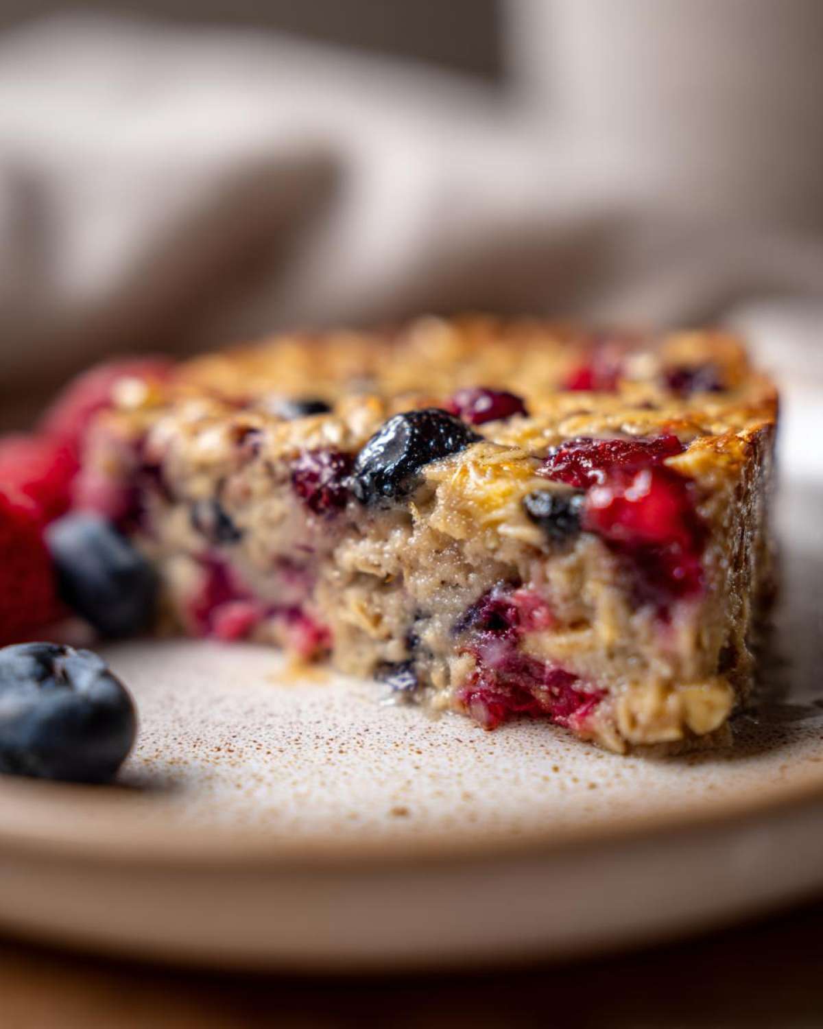 Kawałek pieczonej owsianki z owocami, jagodami i malinami na talerzu.