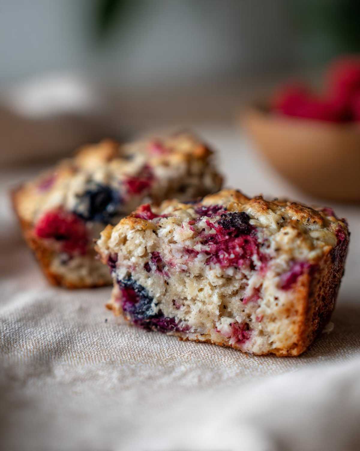 Przekrojona pieczona owsianka z owocami, malinami i borówkami, na lnianym obrusie.