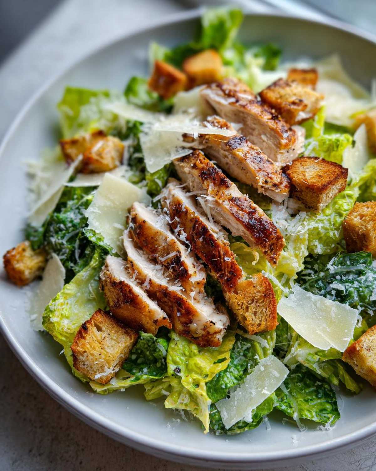 Zdjęcie zbliżeniowe Sałatka Cezar z grillowanym kurczakiem, grzankami i parmezanem.