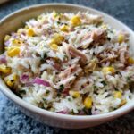 Zdjęcie z bliska sałatki z tuńczykiem i ryżem, z kukurydzą i czerwoną cebulą w misce.