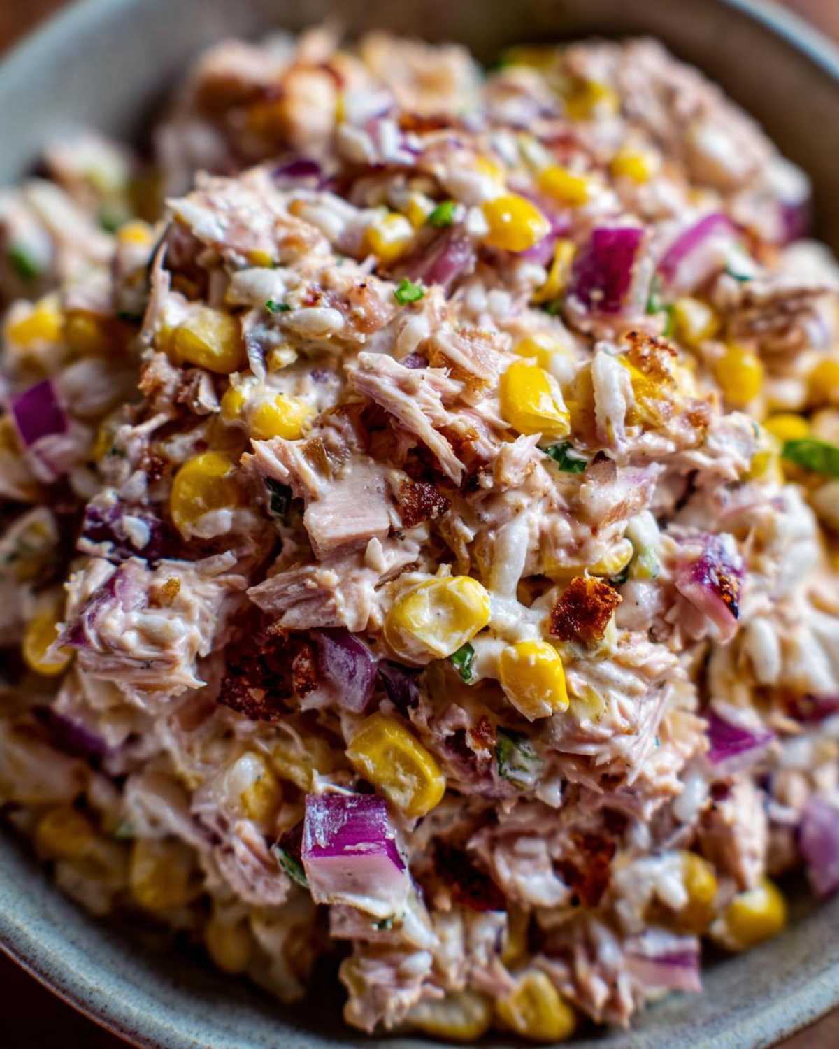 Zdjęcie z bliska sałatki z tuńczykiem i ryżem, z kukurydzą i czerwoną cebulą.