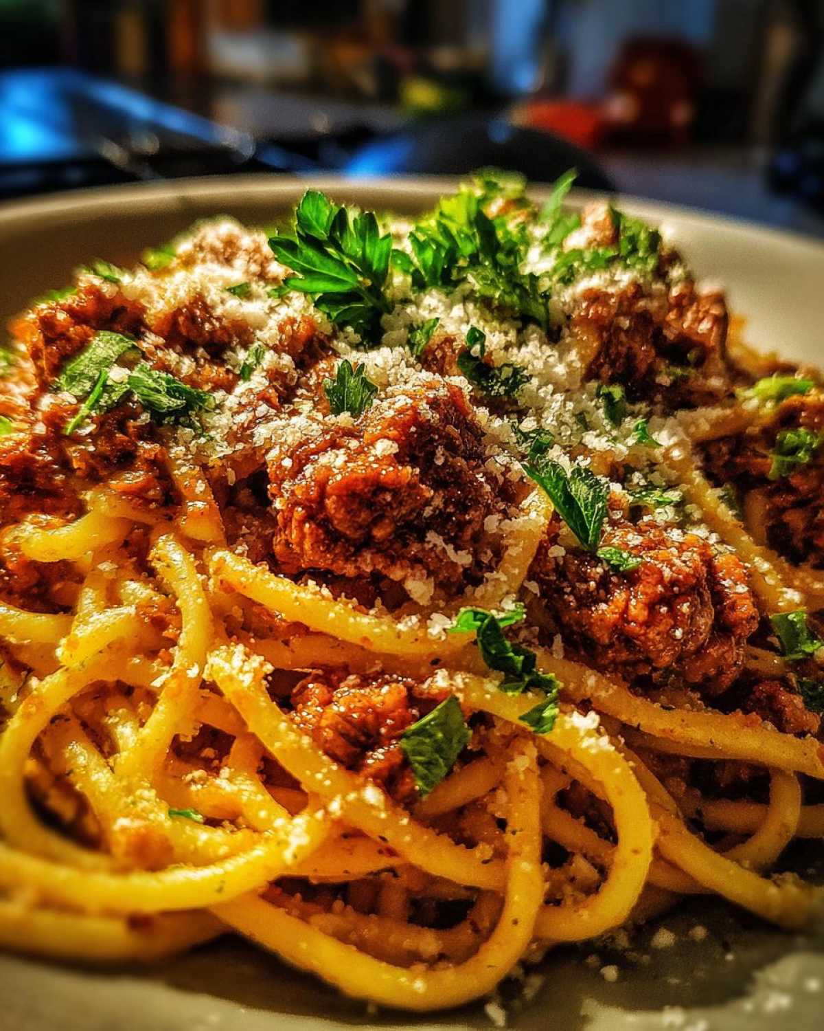 Zdjęcie zbliżeniowe spaghetti bolognese posypanego serem i pietruszką.