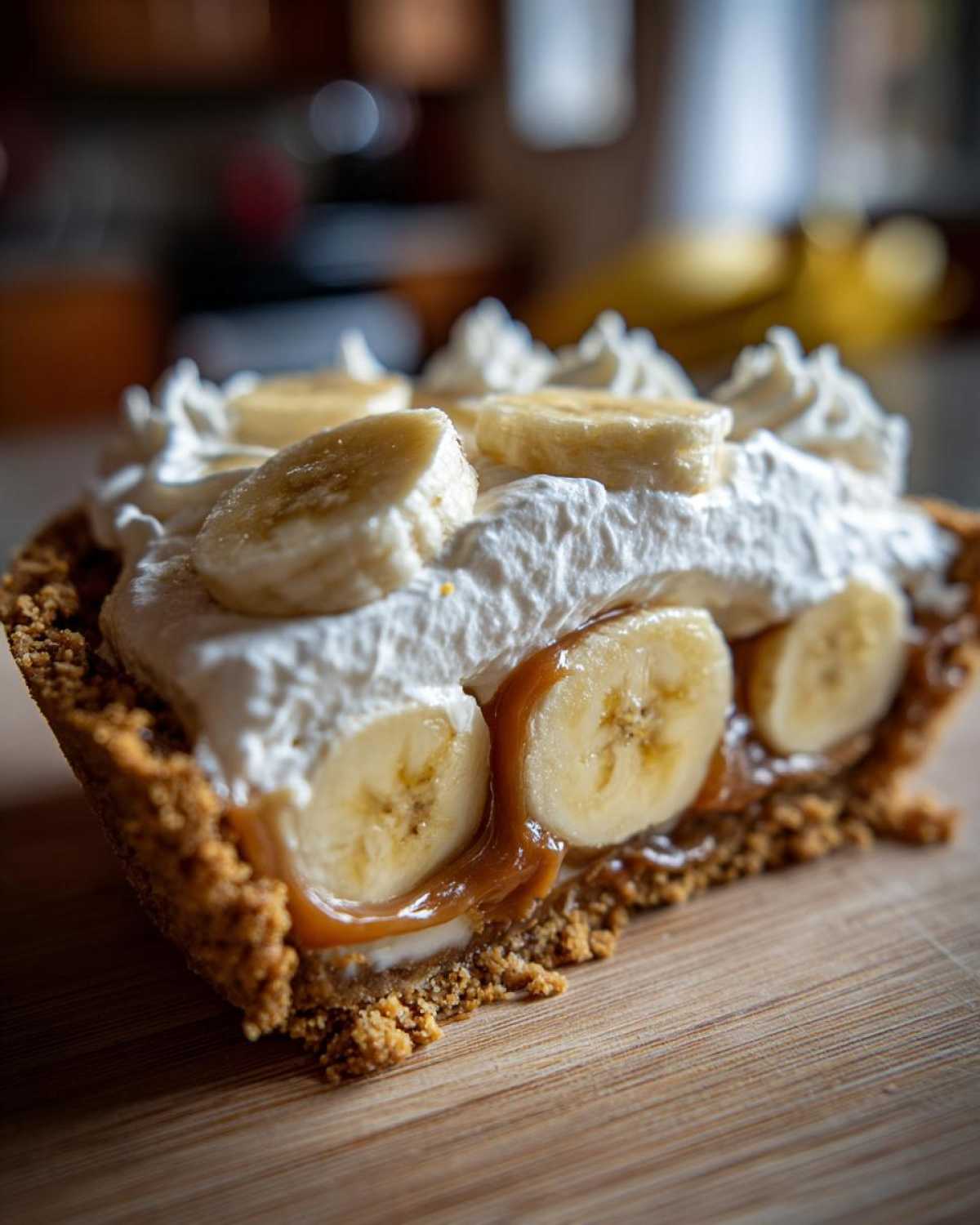 Kawałek pysznego banoffee pie bez pieczenia z warstwami bananów, karmelu i bitej śmietany na kruchym spodzie.