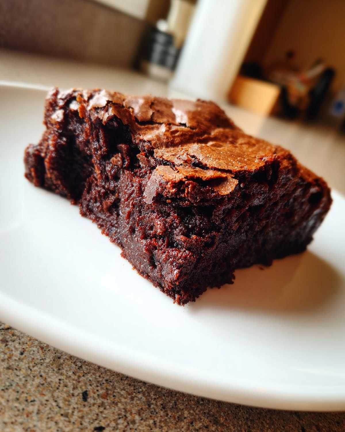 Kawałek wilgotnego brownie z whisky na białym talerzu, z widoczną chrupiącą skórką.