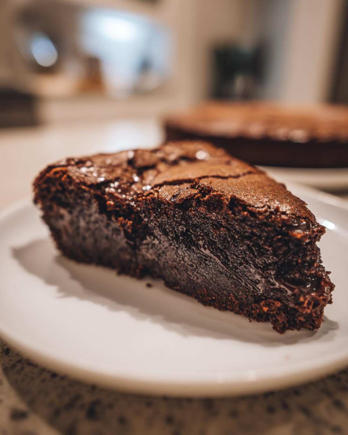 Kawałek wilgotnego brownie z whisky na białym talerzu, z widocznym błyszczącym wierzchem.