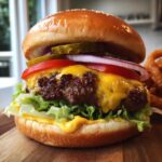 Klasyczny burger wołowy z serem, sałatą, pomidorem, ogórkiem kiszonym i cebulą na desce.