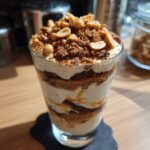 Deser Snickers w pucharku z warstwami kremu, ciastek, czekolady i orzeszków ziemnych.