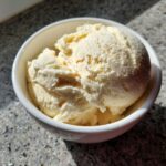 Zbliżenie na kremowe domowe lody waniliowe w białej miseczce, idealne na deser.