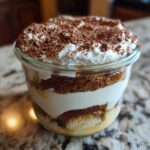 Warstwowe fit tiramisu bez cukru w szklanym słoiczku, posypane kakao.