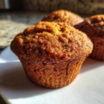 Zbliżenie na puszyste muffiny dyniowe na białym talerzu, idealne na jesień.