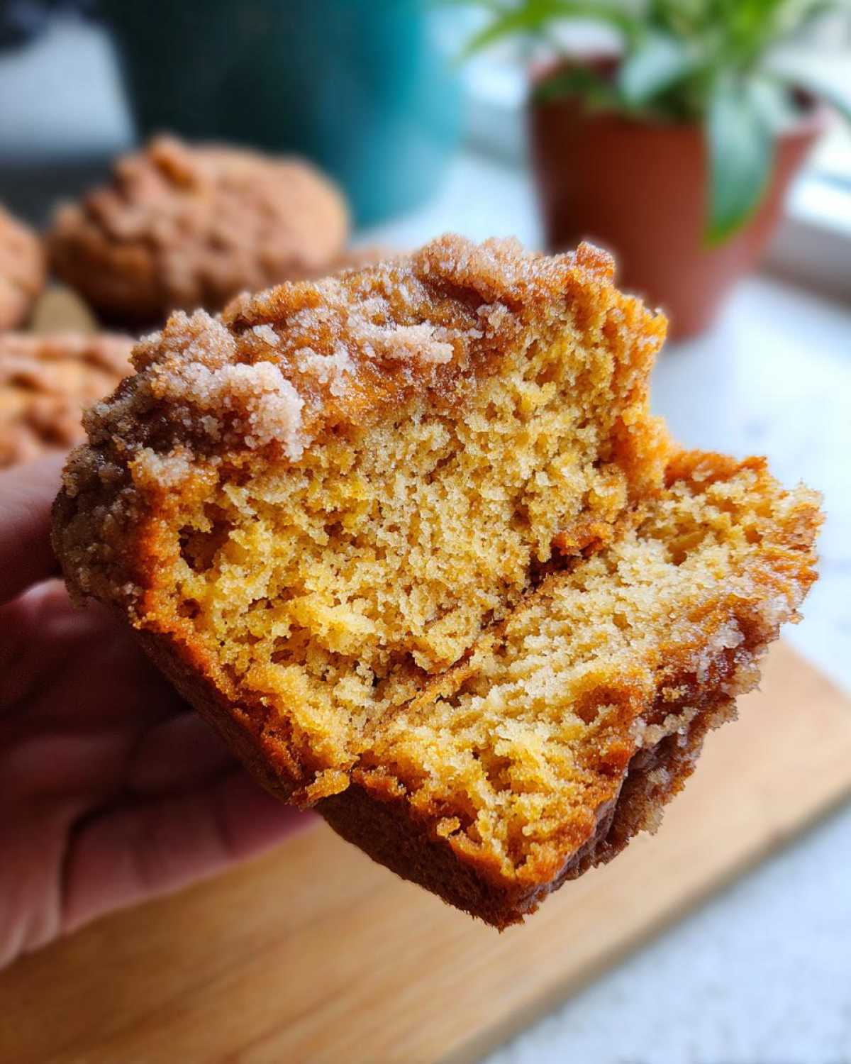 Przekrojony na pół muffin dyniowy z cynamonem, widoczna wilgotna struktura ciasta i kruszonka na wierzchu.