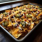 Nachos zapiekane z serem, fasolą, kukurydzą i jalapeño na blasze.