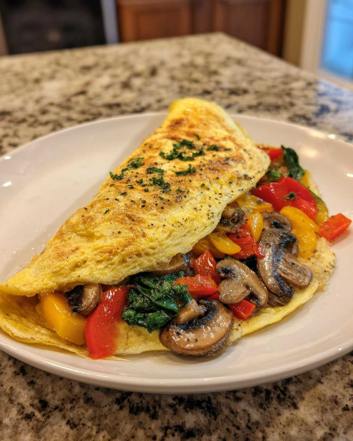 Omlet białkowy z warzywami: pieczarki, papryka i szpinak, posypany szczypiorkiem.