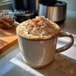 Zbliżenie na kubek z Pumpkin Spice Latte, ozdobiony bitą śmietaną i cynamonem.