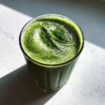 Szklanka pełna zielonego smoothie z jarmużu i banana, ozdobiona nasionami chia.