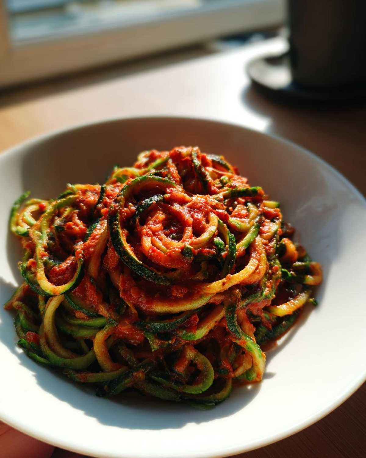 Miseczka pełna spaghetti z cukinii z sosem pomidorowym, danie prezentuje się apetycznie.