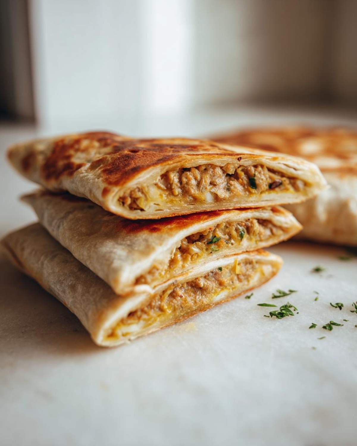 Przekrojona na pół zawijana tortilla z TikToka, ukazująca bogate nadzienie z mięsa i przypraw, ozdobiona natką pietruszki.