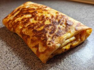 Zawijana tortilla z TikToka, złocista i lekko przypieczona, z widocznym nadzieniem w środku.