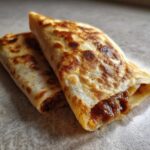 Dwie zawijane tortille z TikToka, idealnie zrumienione, z widocznym farszem.