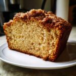Puszyste ciasto drożdżowe z kruszonką na białym talerzu, widoczny przekrój ciasta.