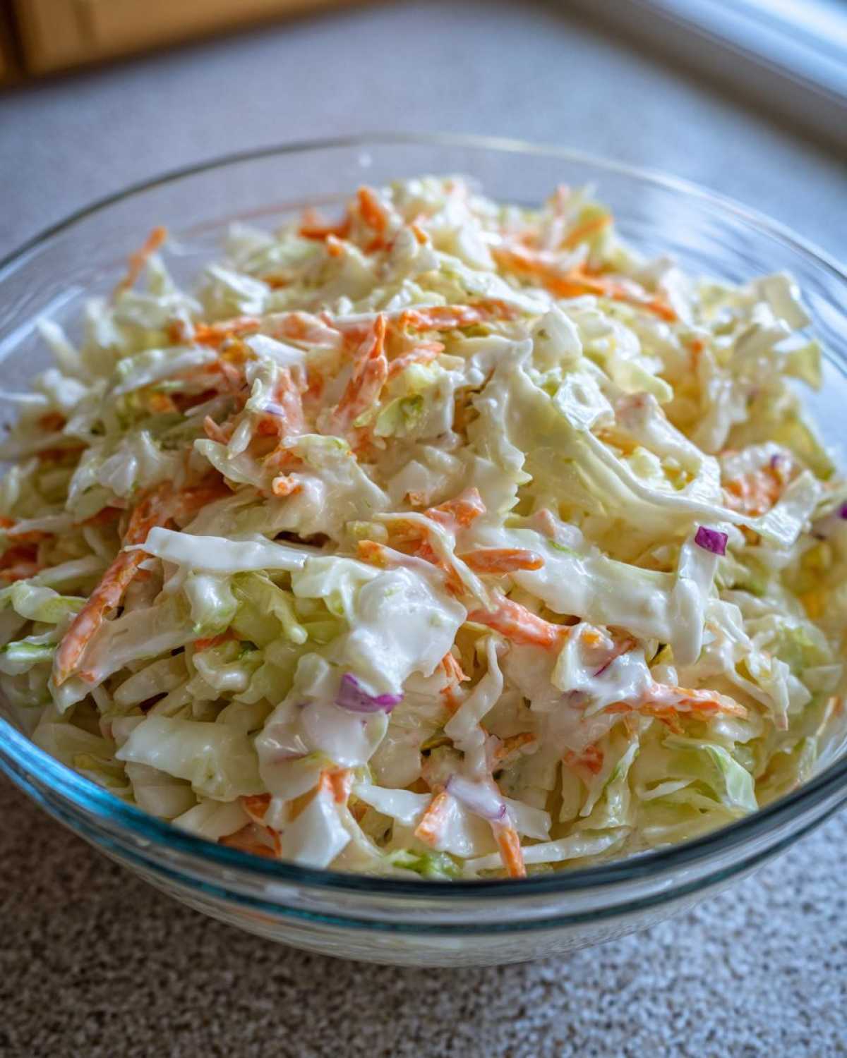 Zbliżenie na miskę pełną świeżego coleslaw domowy z posiepaną czerwoną cebulą.