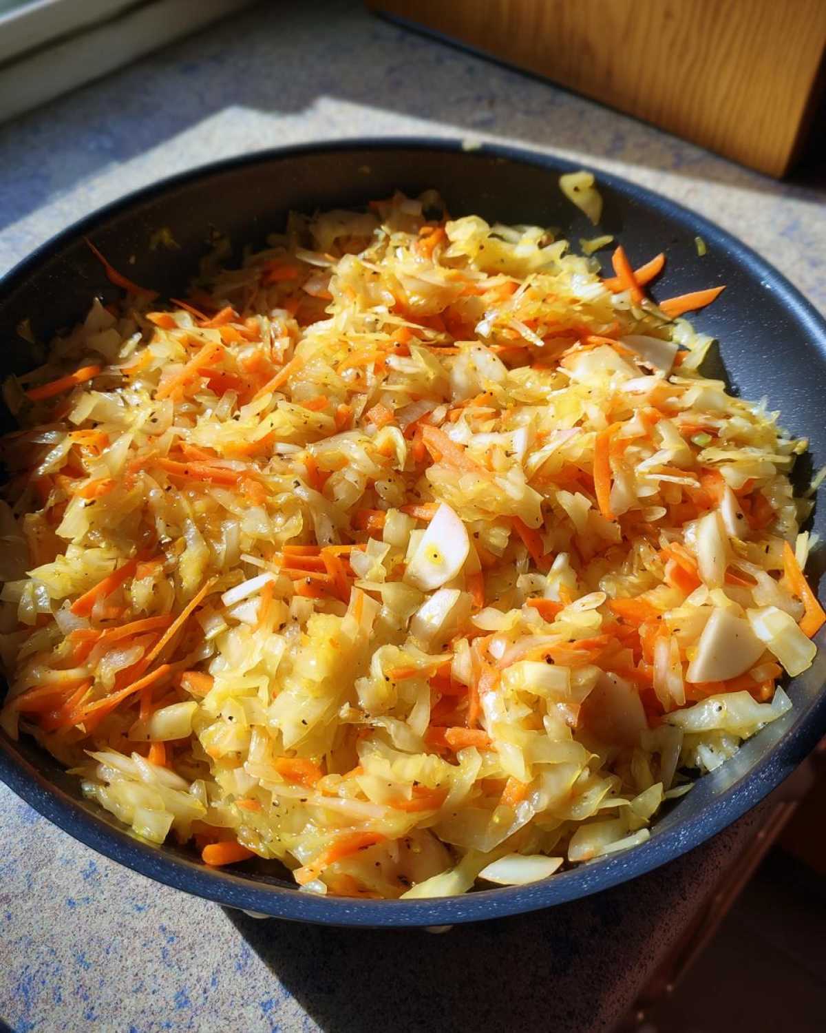 Zbliżenie na jesienną surówkę z kapusty z marchewką i czosnkiem w patelni.