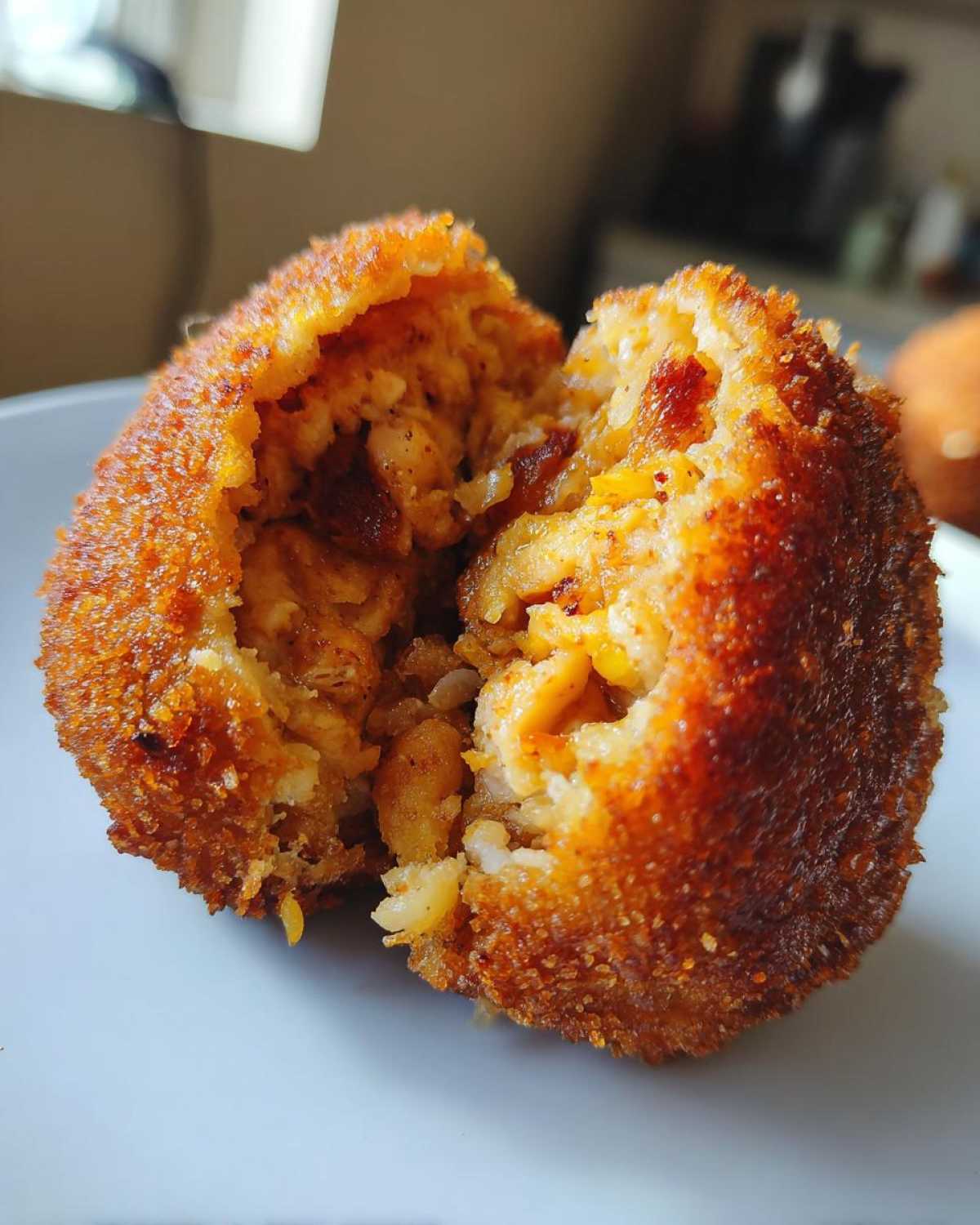 Przekrojony kotlet ziemniaczany z kurczakiem, widoczne chrupiące panierka i farsz z ryżu i kurczaka.
