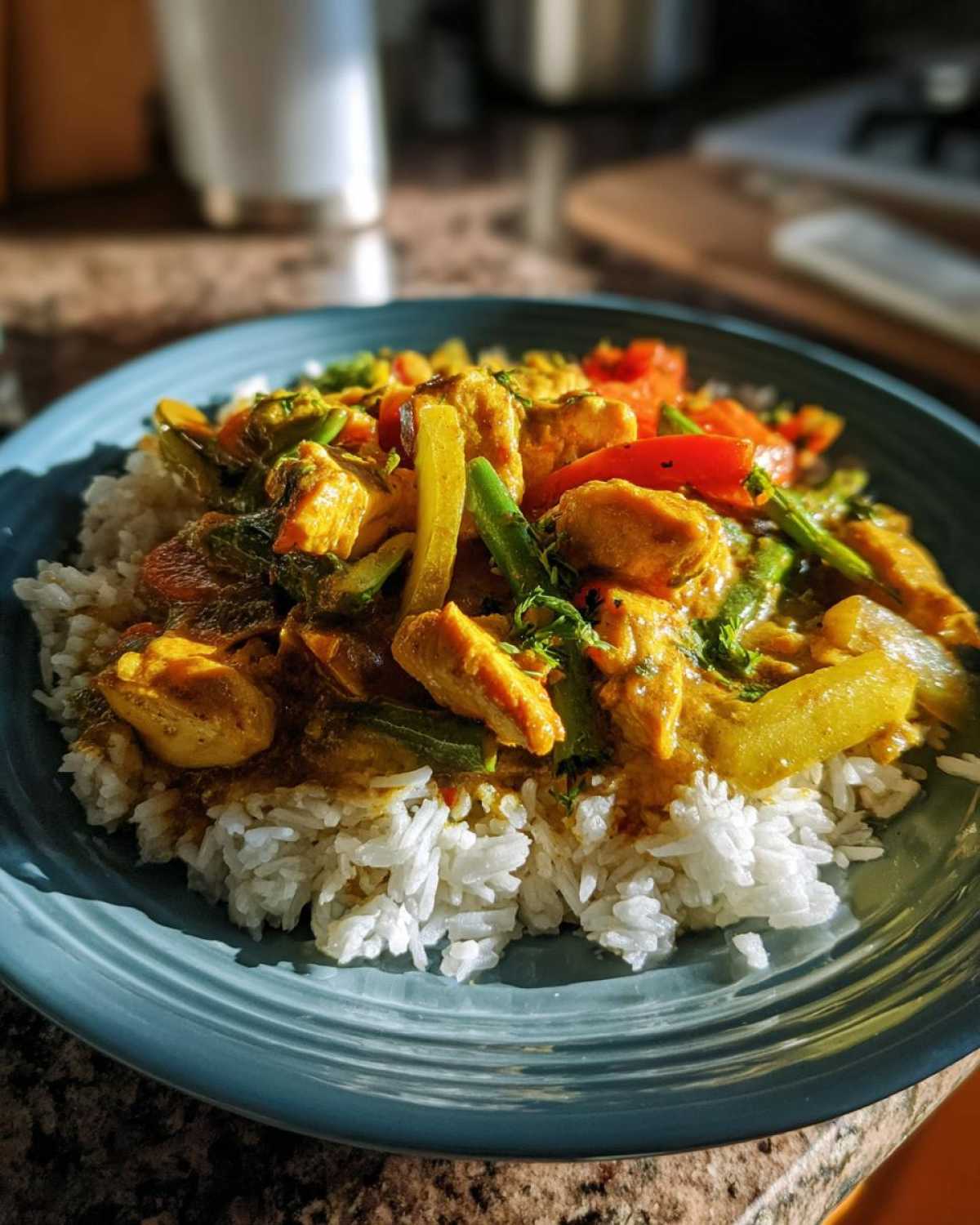 Talerz pełen łagodnego kurczaka curry z warzywami podany na białym ryżu.
