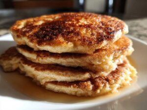 Stos puszystych placków bananowych posypanych cynamonem, polanych syropem.