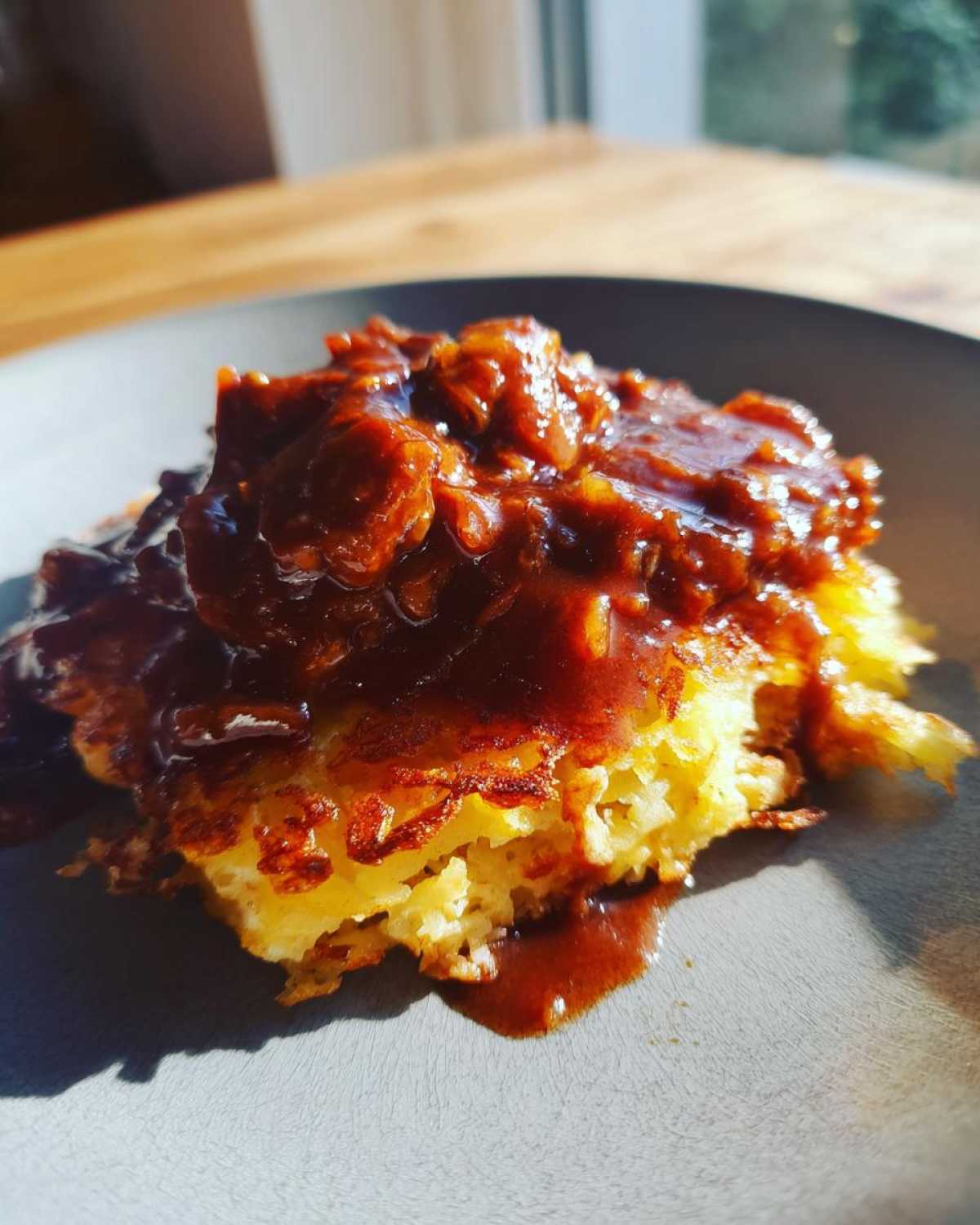 Zbliżenie na placki ziemniaczane po węgiersku polane gęstym, brązowym sosem.
