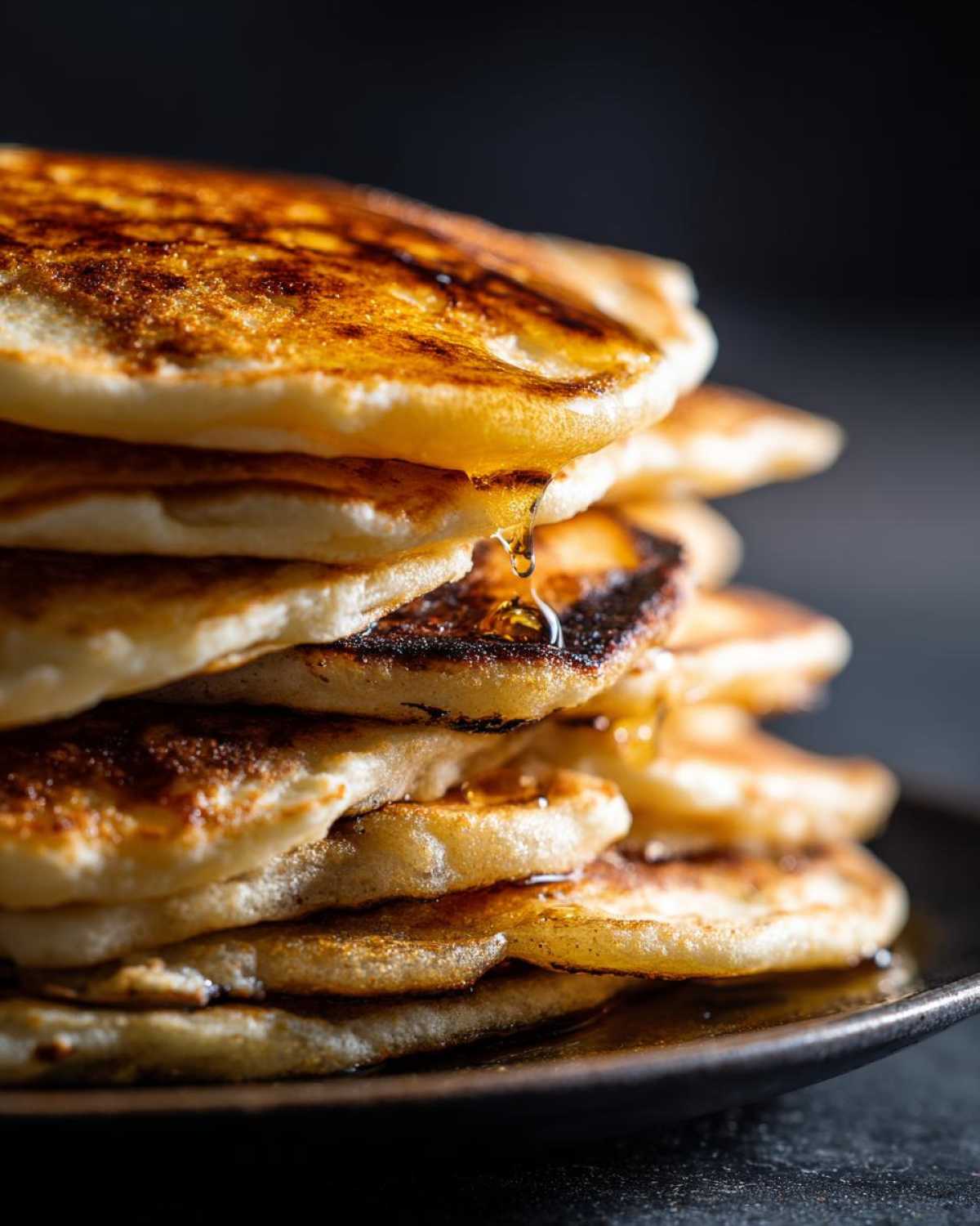 Stos puszystych pancakes amerykańskich polanych syropem.