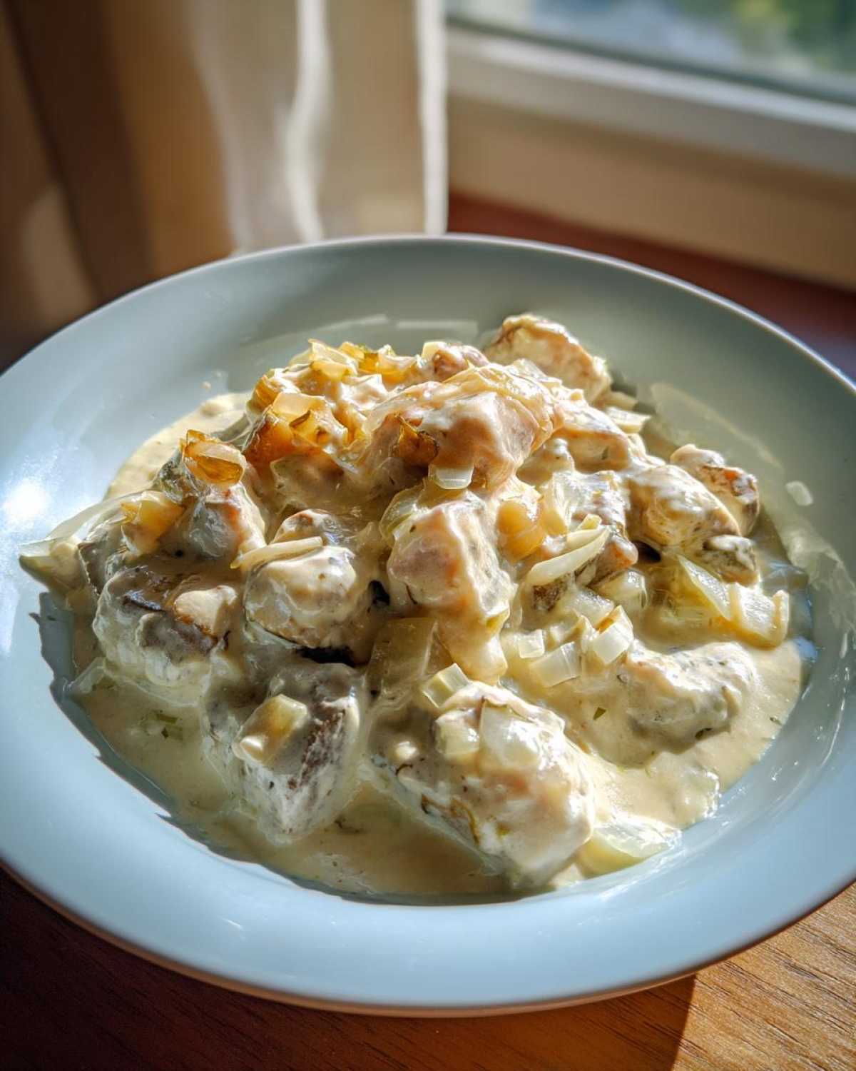 Miseczka pełna śledzi w śmietanie z cebulką, gotowa do podania.