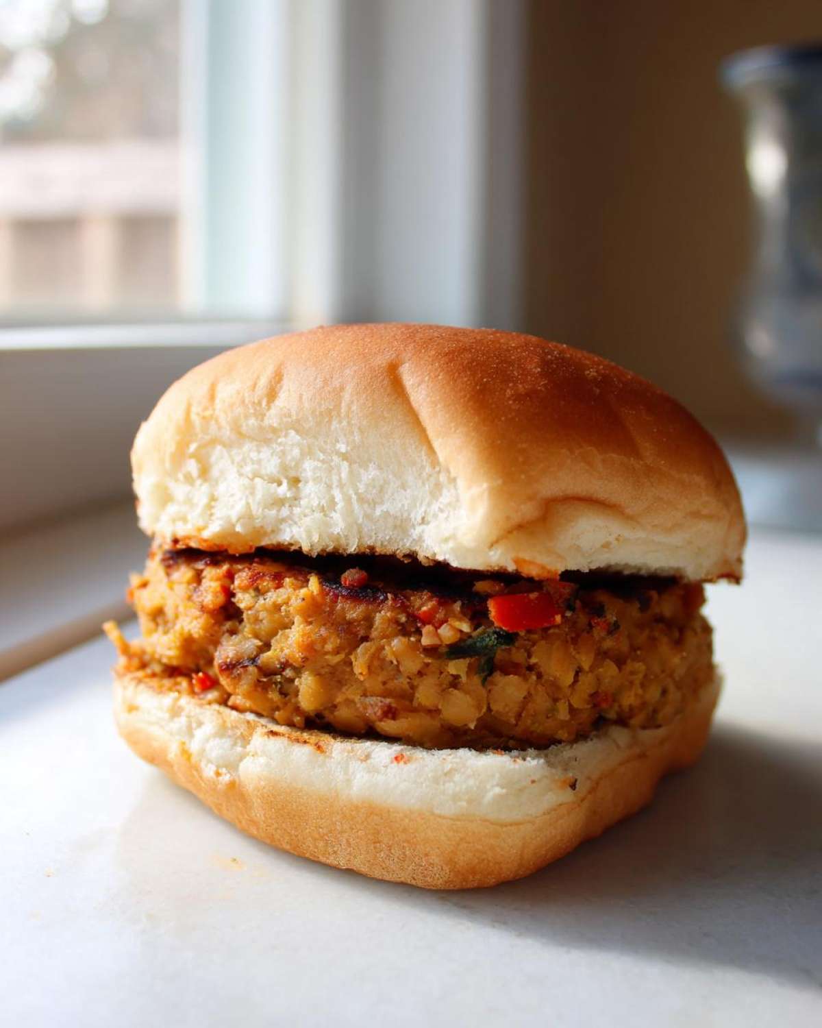 Zbliżenie na soczysty burger wegetariański z kotletem z ciecierzycy w miękkiej bułce.