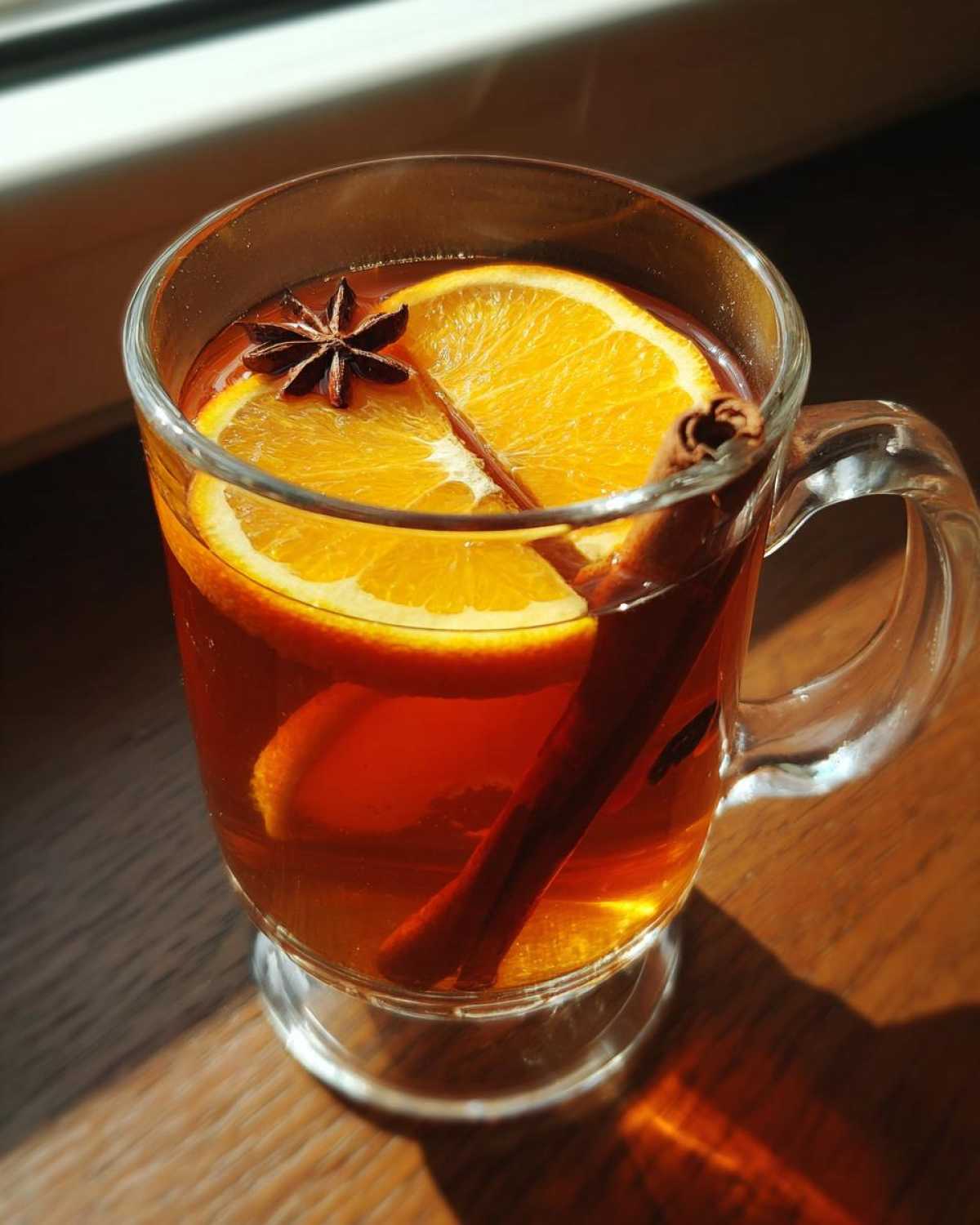 Szklanka aromatycznej herbaty zimowej z pomarańczą, laską cynamonu i anyżem.