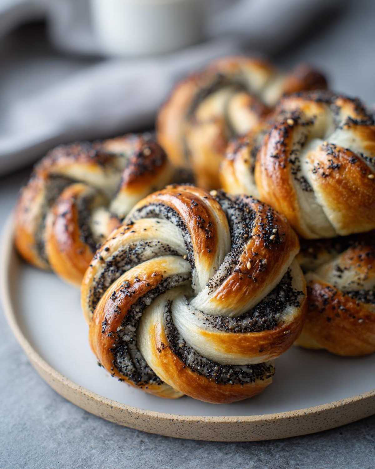 Zbliżenie na piękną makową gwiazdę drożdżową, udekorowaną makiem i sezamem, na ceramicznym talerzu.