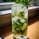 Szklanka wypełniona lodem, limonką i świeżą miętą, idealny Drink Mojito.