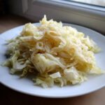 Zbliżenie na porcję pysznej, podsmażonej Kapusta zasmażana podanej na białym talerzu.