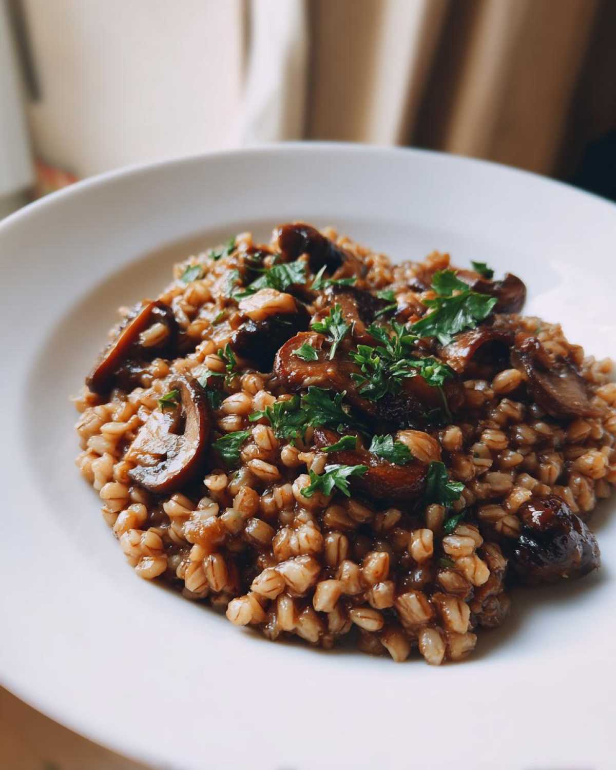 Zbliżenie na porcję kremowego Kaszotto z grzybami, posypane świeżą natką pietruszki.