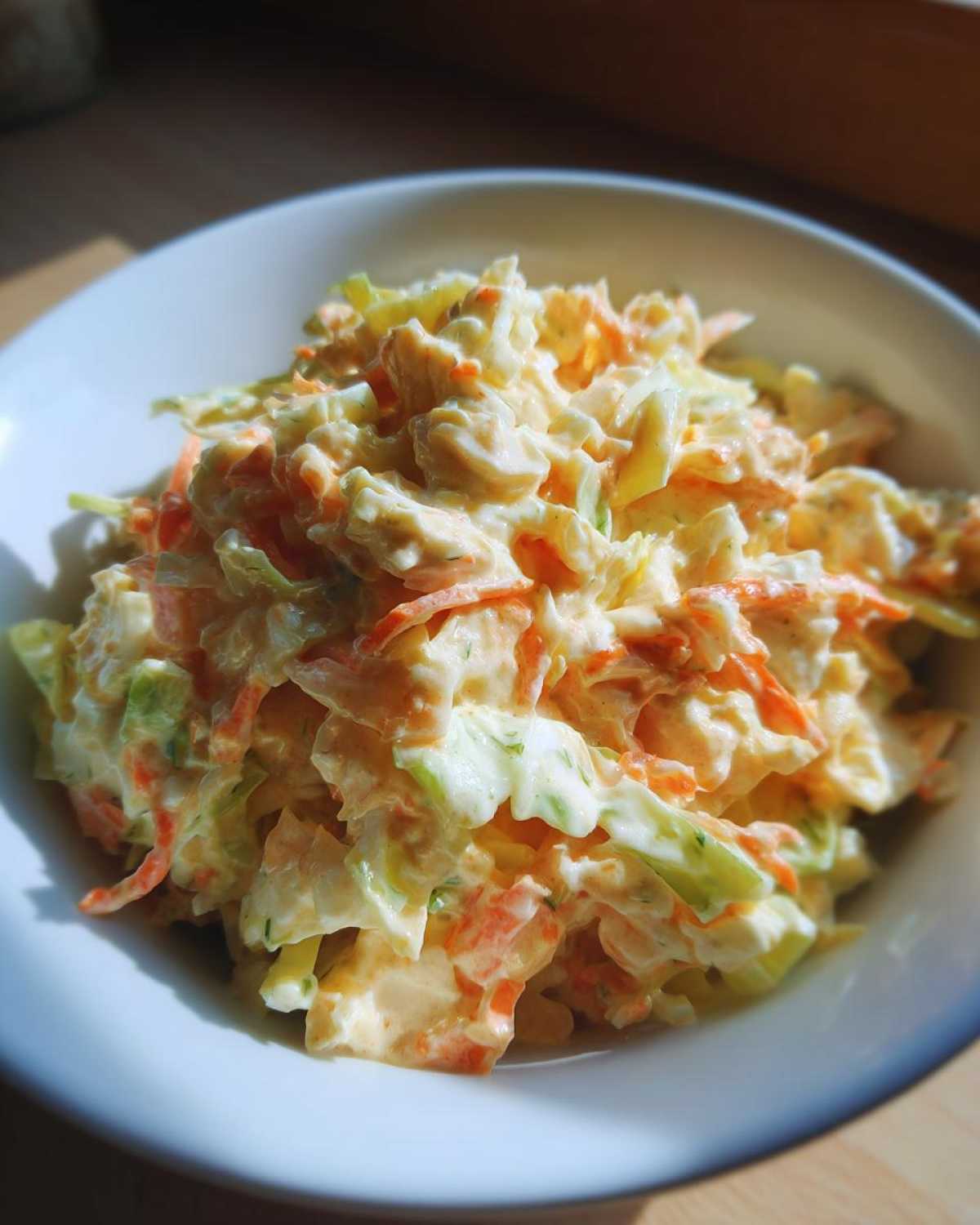 Zbliżenie na miskę pełną kremowej sałatki Coleslaw domowa z tartą marchewką i kapustą.