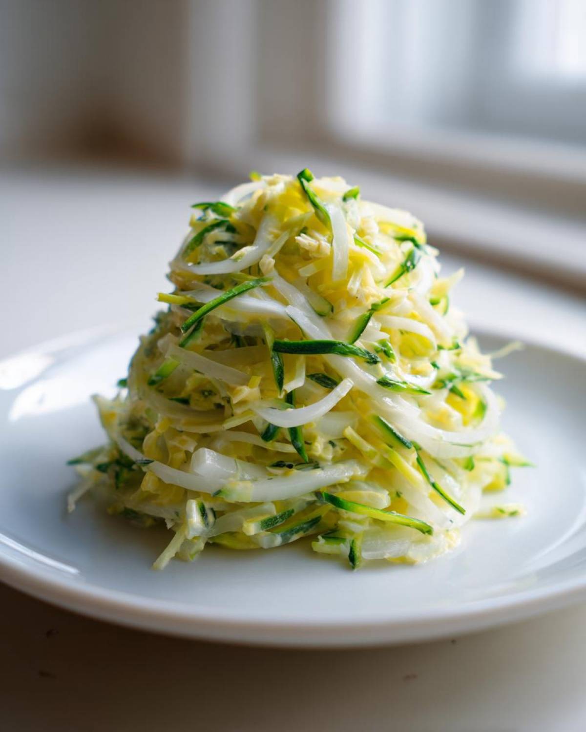 Porcja Surówki z pora z tartym cukinią na białym talerzu.