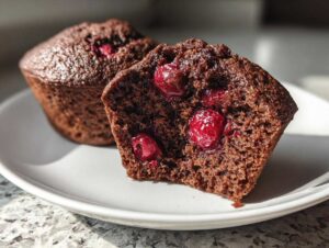 Przekrój muffinki czekoladowe z wiśniami pokazujący wilgotne wnętrze i soczyste owoce.
