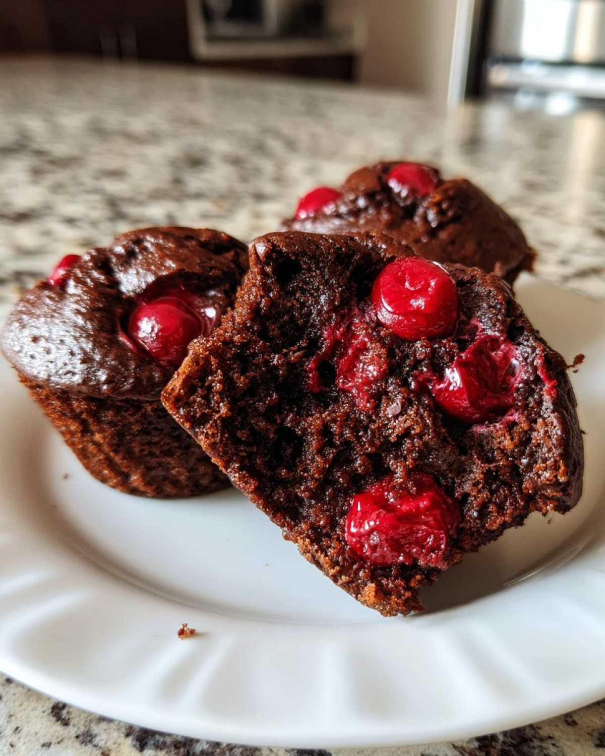 Zbliżenie na przekrojone muffinki czekoladowe z wiśniami, ukazujące wilgotny środek.