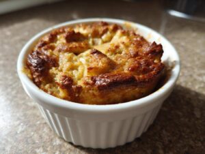 Złocista i przypieczona owsianka pieczona z jabłkiem w małej, białej kokilce.