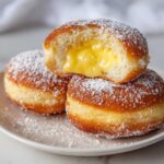 Zbliżenie na pączki z adwokatem, jeden przekrojony ukazujący kremowe żółte nadzienie.
