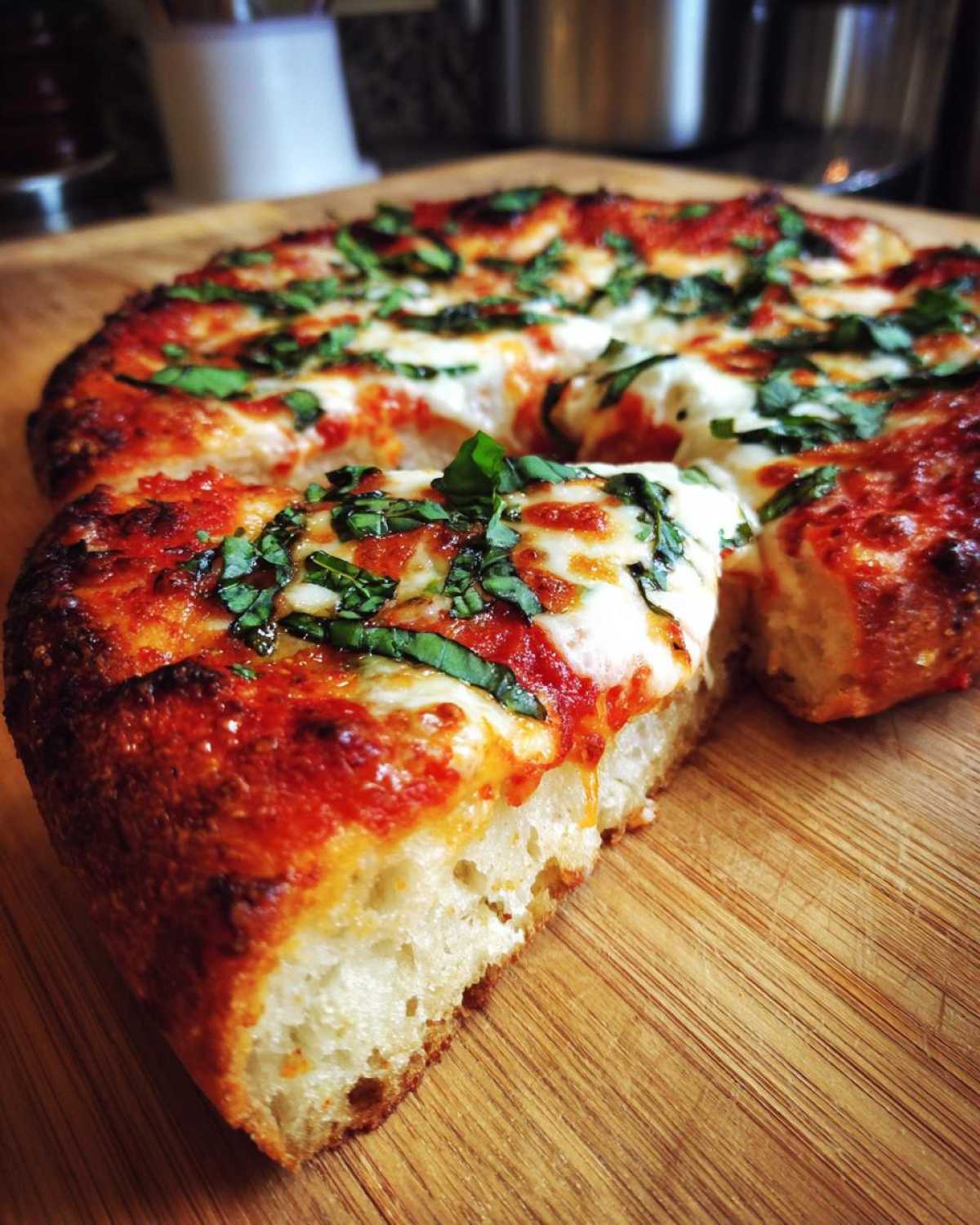 Zbliżenie na kawałek puszystej Pizza domowa margarita z ciągnącym się serem i bazylią na desce.